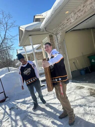 Youngsters crew in team jerseys carrying furniture out of a house
