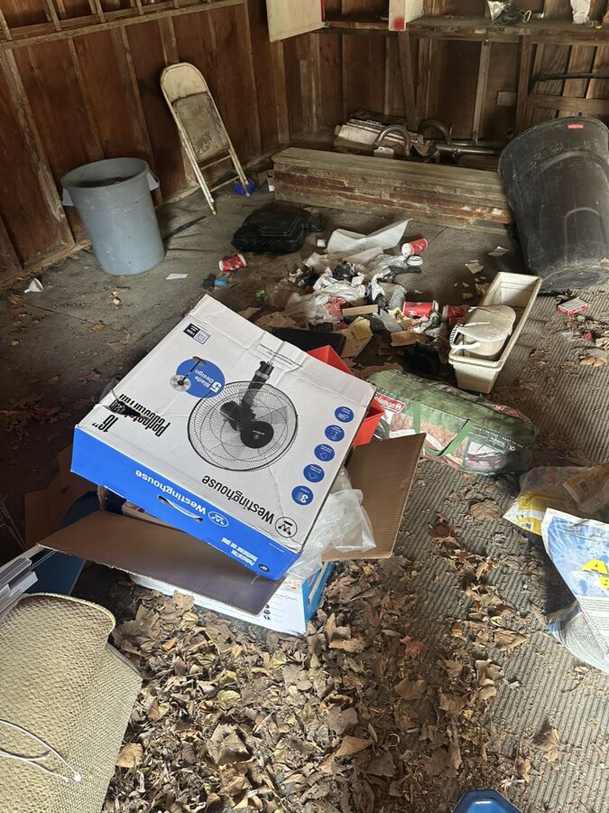 Garage floor covered in junk, boxes and leaves